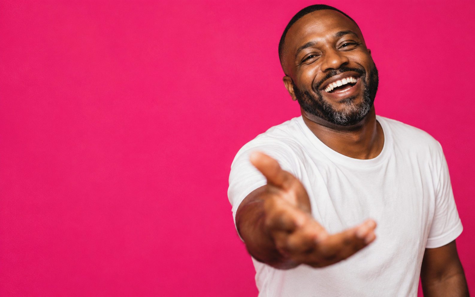Man laughing and reaching toward the camera against a magenta backdrop