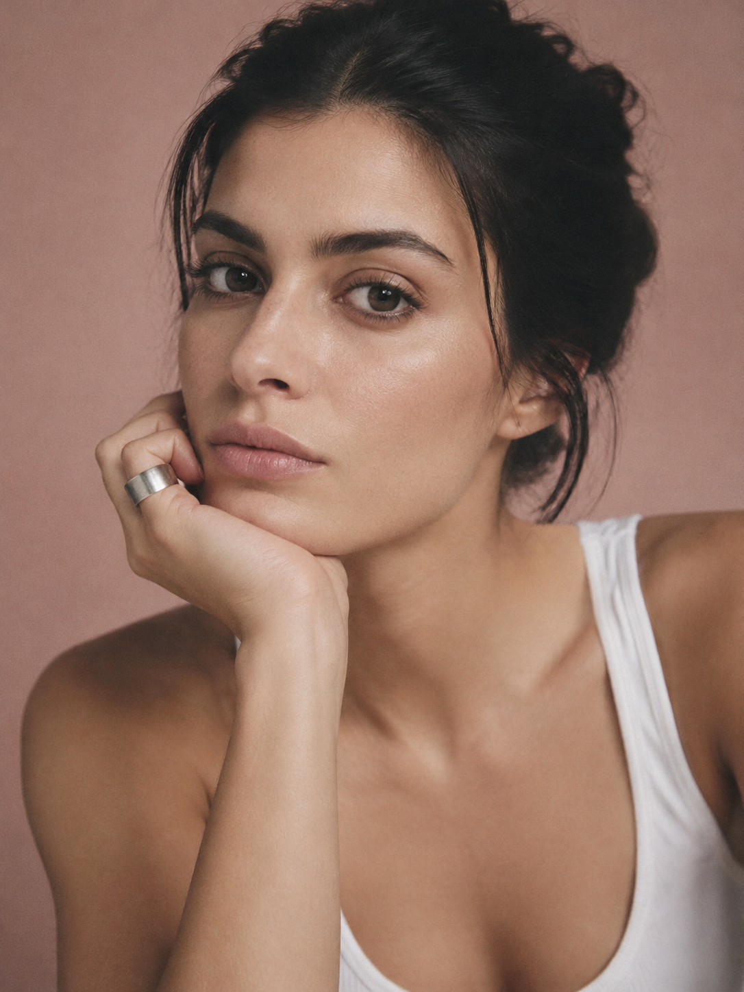 Woman resting her chin on her hand against a pink backdrop